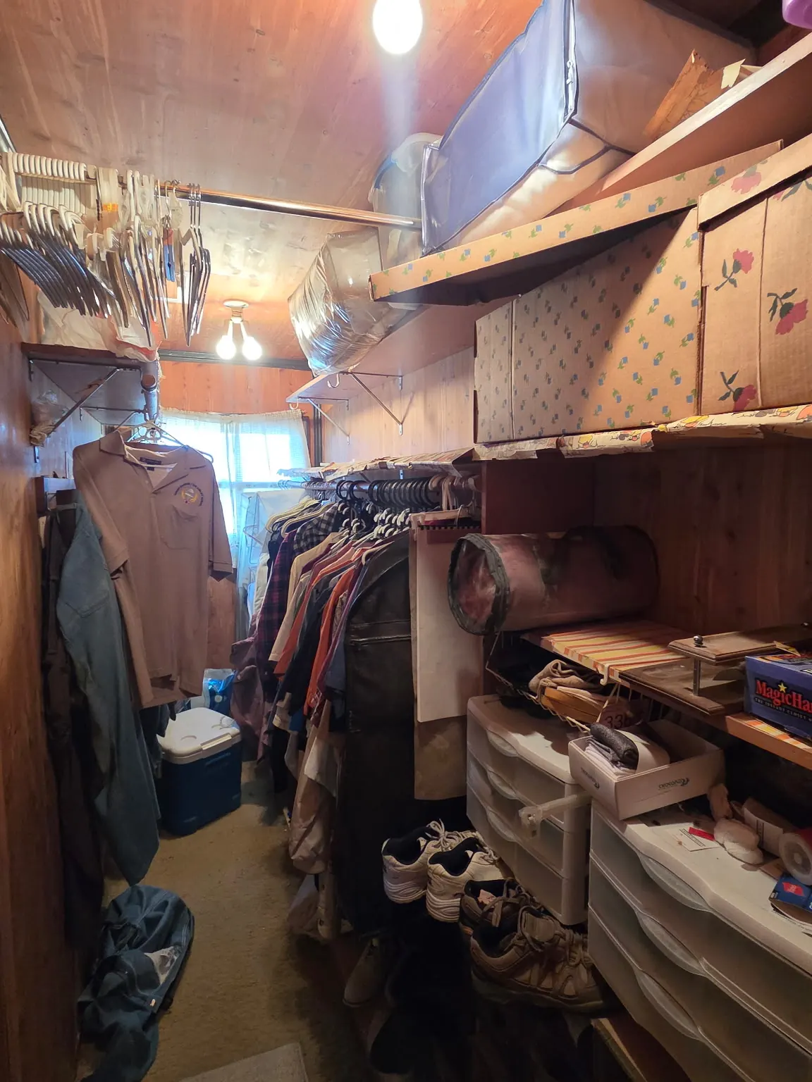 Walk-in cedar closet before: packed with clothes, boxes and bins