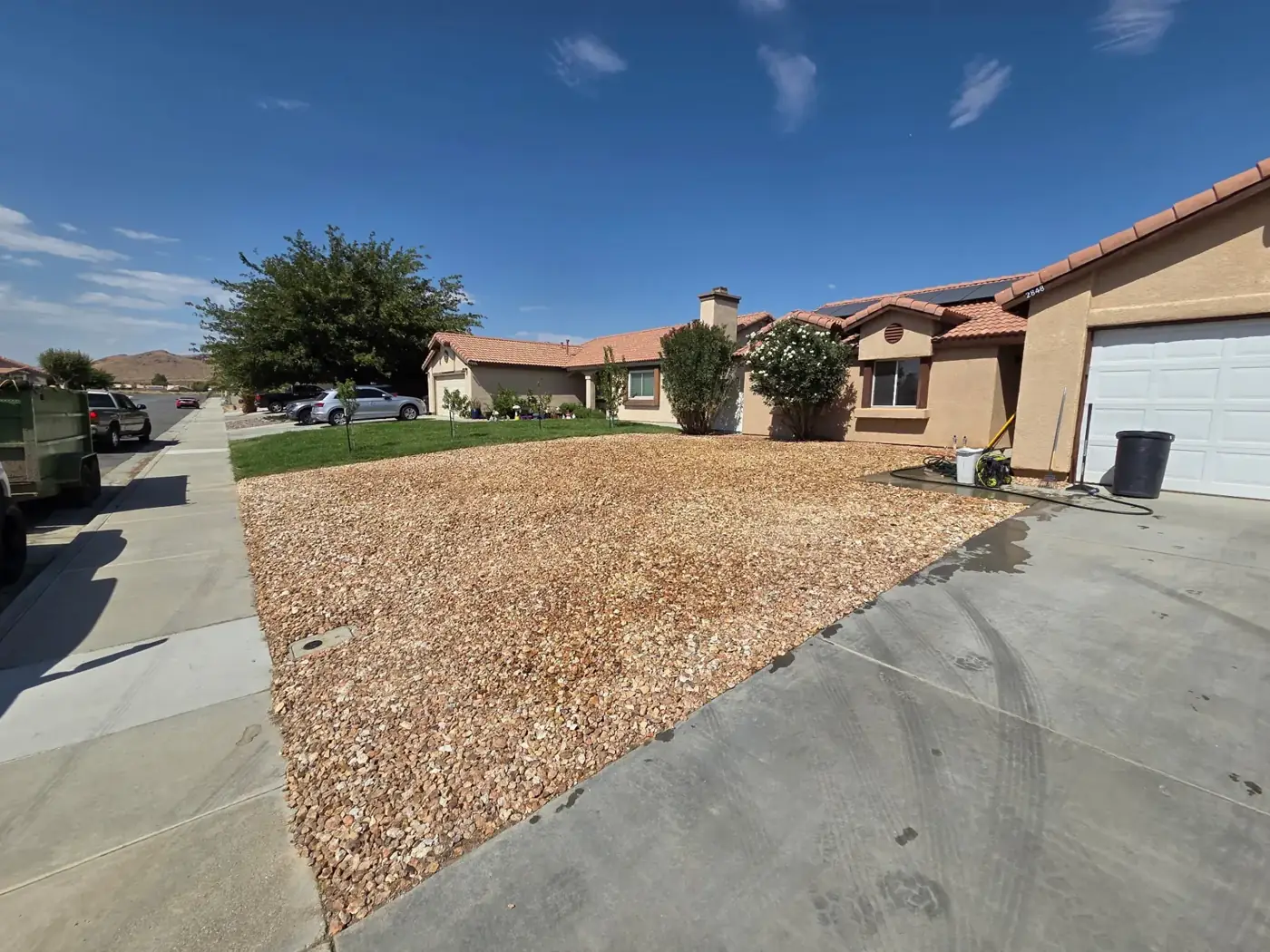 Front yard after, street view: rock spread from driveway to neighbor's lawn